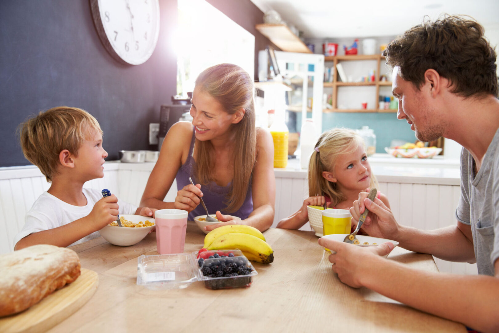 A family eating cereal and fruit at the table.